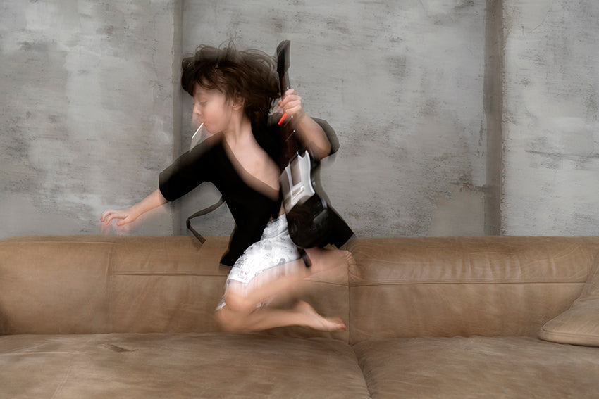 niño con guitarra saltando en el sofa
