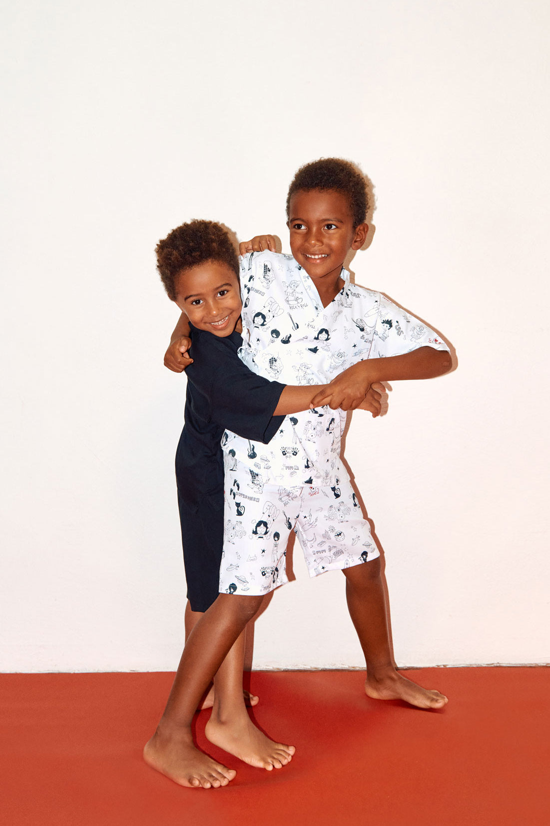 dos niños jugando de pie, uno niño con conjunto Jinbei en algodón impreso y el otro con conjunto negro jinbei en viscosa de Forever 2 